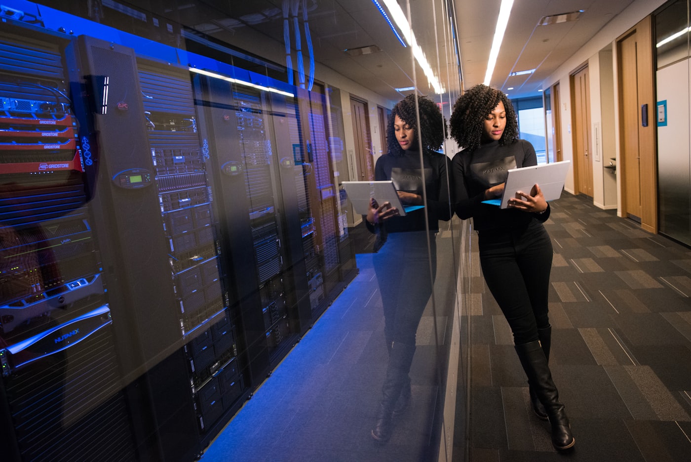A technology worker walking through a server corridor with a tablet